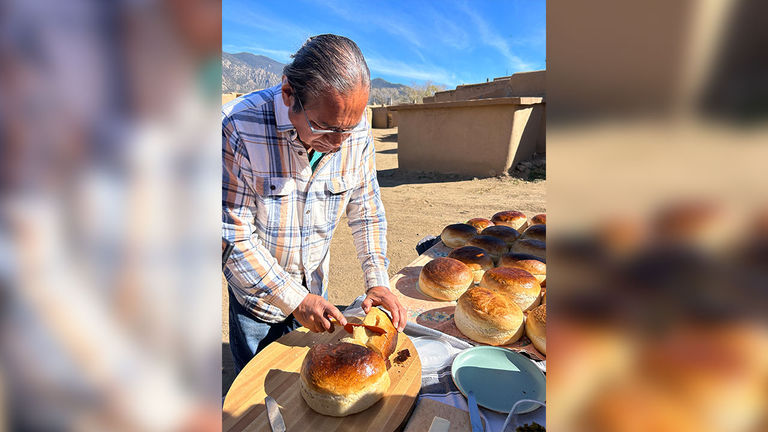 Taos Pueblo resident Geronimo bakes bread with guests in a traditional horno oven.